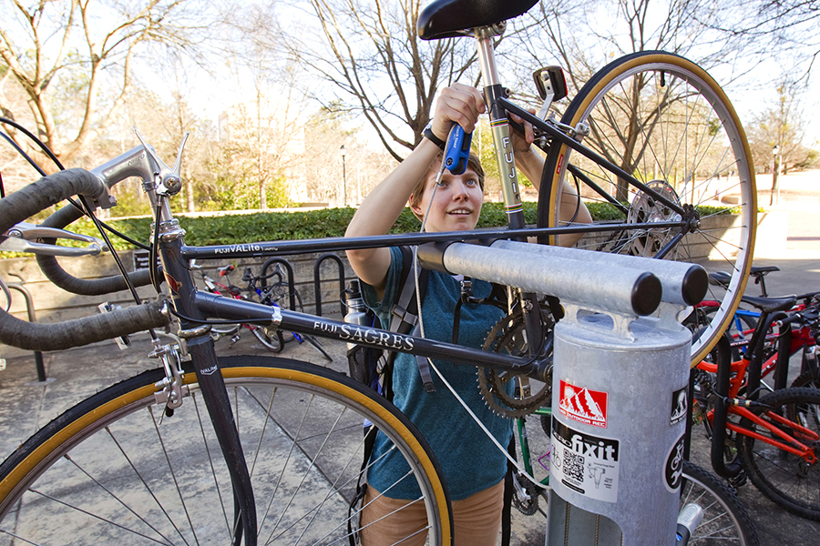 Person fixing their bike at a FixIt station on campus.